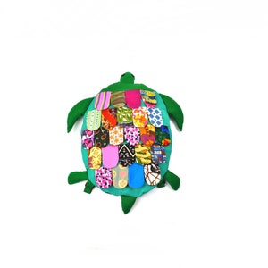 May include: A green fabric turtle with a patchwork shell made of colourful fabric scraps. The turtle is a stuffed toy.