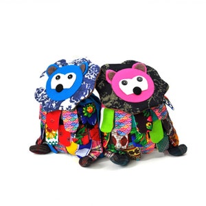 May include: Two colourful patchwork stuffed animals with animal faces. The animal on the left has a blue face and the animal on the right has a pink face.