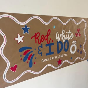 May include: A rectangular brown paper banner featuring the text Red, white & I DO and SAM'S BACHELORETTE in red and blue. The design includes a white diamond ring illustration, red and blue hearts, and various stars on a wavy white border.
