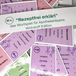 May include: A collection of cards with text and illustrations, featuring the phrase "Rezeptfrei erklärt" and "das Wortspiel für Apothekenteams Wirkstoff Edition." The cards have a purple and green color scheme, with various medical terms.