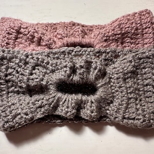May include: Two crocheted headbands, one gray and one pink, with a bow detail.
