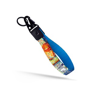 May include: A blue and orange key chain with a black metal clasp and a ring. The key chain features a painting by Vincent van Gogh. The text "Vincent van Gogh" is printed on the key chain.