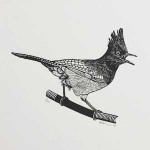 May include: Black and white linocut print of a bird with a crested head, perched on a branch. The bird is singing with its mouth open. The print is numbered 1/60 and signed "Ruthie '21".