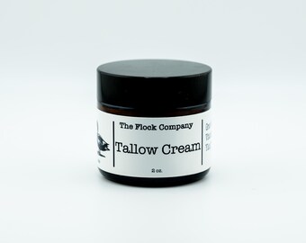 May include: A small amber glass jar with a black screw-top lid, containing 2 oz. of Tallow Cream. The white label features a black graphic of a bird, the text The Flock Company, and the product name Tallow Cream in a clear, black font.