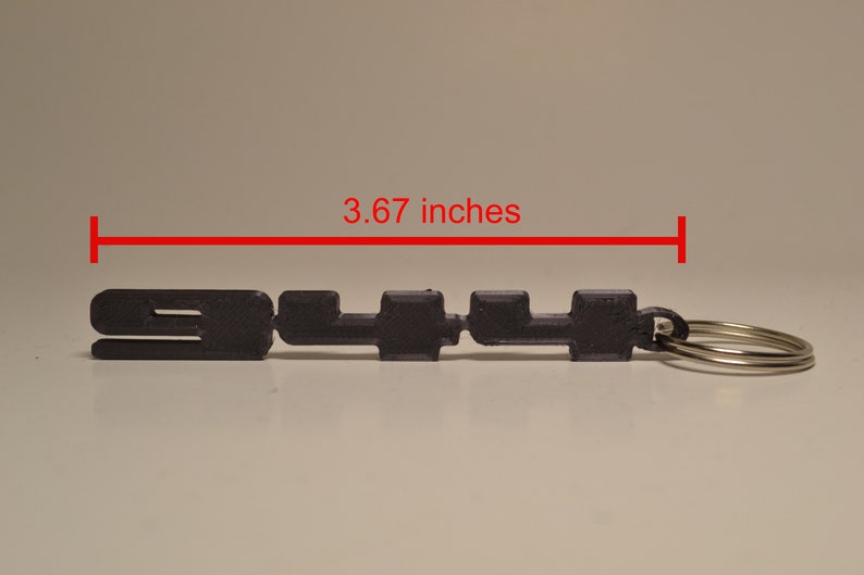 May include: A black 3D printed keyring with the text "911" and a silver key ring. The keyring is 9.3 cm long.
