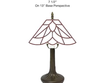 May include: A table lamp with a dark brown, textured tree-trunk base and a geometric stained glass shade featuring white panels outlined in dark red. The text 7 1/2" On 13" Base Perspective is displayed above the lamp, indicating its dimensions.