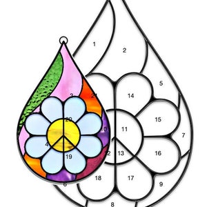 May include: A stained glass pattern for a peace sign with a daisy in the centre. The pattern is in the shape of a teardrop and is 5 inches by 7 1/2 inches.