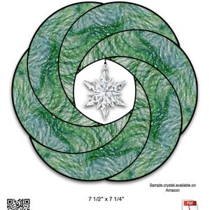 May include: A Christmas Mobius wreath made of green and blue stained glass, with a snowflake crystal in the center. The wreath measures 7.5 x 7.25 inches. The text "Christmas Mobius Wreath" is at the top.