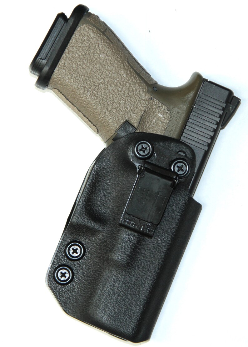 Puede incluir: Una funda de cuero negra con un clip y dos tornillos. Una pistola negra y marr&oacute;n est&aacute; dentro de la funda.