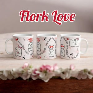 Może przedstawiać: Trzy białe ceramiczne kubki z napisem "Flork Love" nad nimi. Każdy kubek ma inny wzór postaci z kreskówek z sercami, nutami i hiszpańskim tekstem. Kubki stoją na jasnej drewnianej powierzchni.