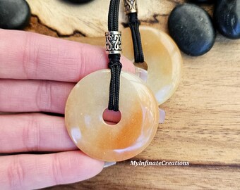 May include: A necklace with two orange and white stone pendants, each with a hole in the center. The necklace is made with black cord and silver beads.