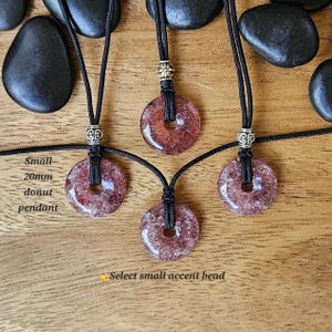 May include: Three necklaces with donut-shaped pendants made of pink and white stone. The pendants are 20mm in diameter and are strung on black cords with silver accent beads. The text "Small 20mm donut pendant" is visible in the image.