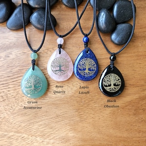 May include: Four necklaces with tree of life pendants made of different stones. The stones are green aventurine, rose quartz, lapis lazuli, and black obsidian.