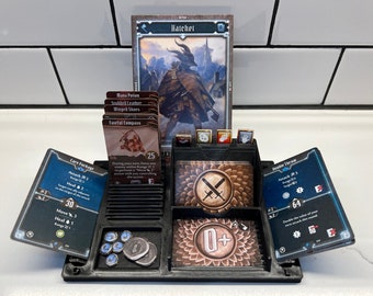 May include: A black and gray 3D printed game organizer with compartments for cards, dice, and tokens. The organizer has a card slot for a character card with the text "Hatchet" and a card slot for a card with the text "Care Package". The organizer also has a slot for a card with the text "Double Tree".