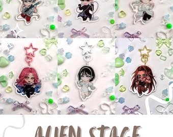 May include: Six colorful anime character keychains with a white background. The keychains feature characters with different hair colors and styles, including pink, blue, black, and blonde. The keychains are labeled "Alien Stage Keychains".