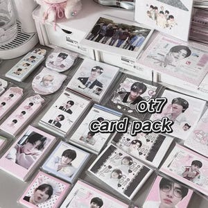 May include: A collection of ot7 card packs featuring various images of people, packaged in clear plastic. The cards are in pink, white, and black packaging. The text "ot7 card pack" is visible on the cards.