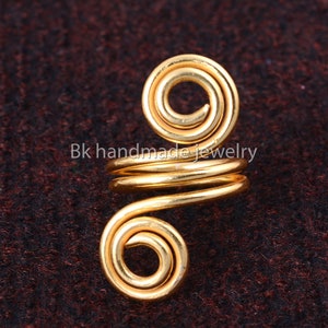 May include: Gold-toned wire ear cuff with a double spiral design. The cuff is made of a single piece of wire that is twisted and shaped into a spiral.