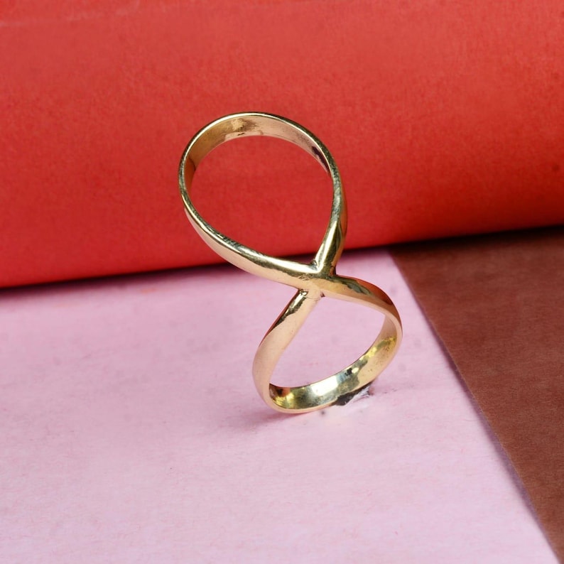 May include: A gold infinity symbol ring. The ring is made of a smooth metal and has a simple design.