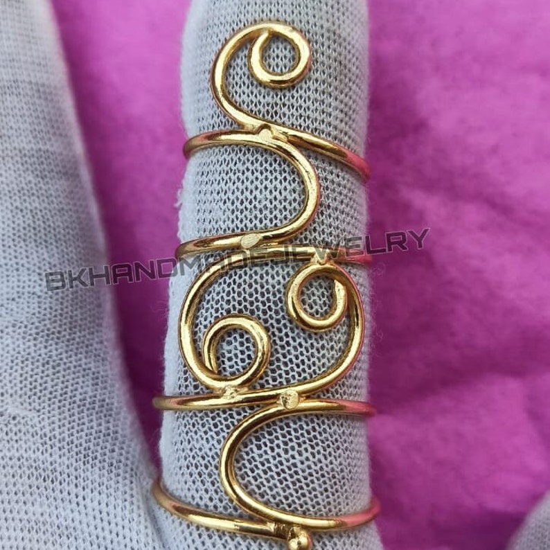 May include: Gold wire ring with a swirling design. The ring is adjustable and can be worn on any finger.
