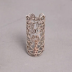 May include: A silver ring with a tree design. The ring is made of intricate swirls and has a textured surface.