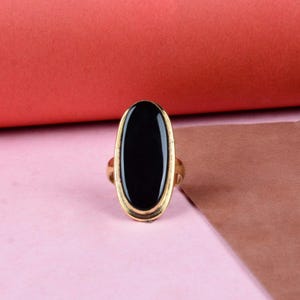 May include: A gold ring with a large oval black stone.
