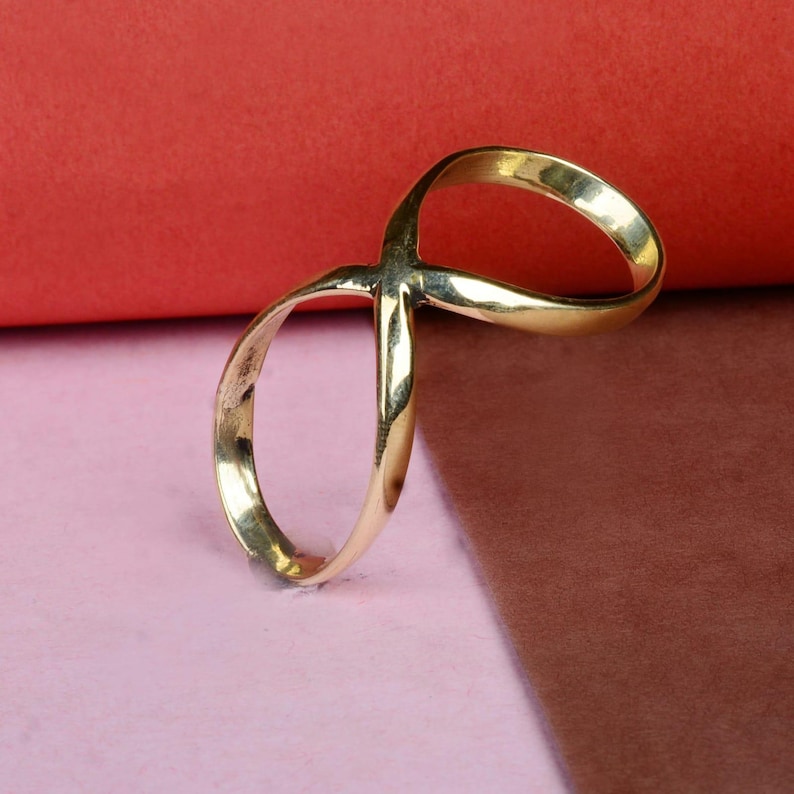May include: A gold infinity ring with a simple design. The ring is made of metal and has a smooth finish.