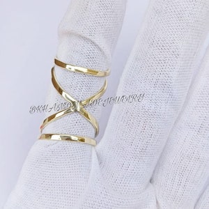 May include: Gold-toned criss-cross ring with a hammered finish. The ring is worn on a finger.