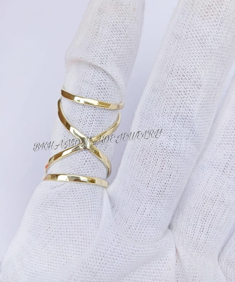 May include: Gold-toned criss-cross ring with a hammered finish. The ring is worn on a finger.