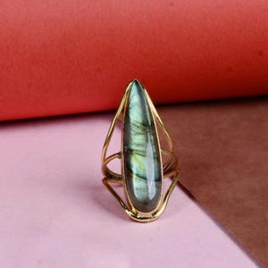 Może przedstawiać: Złoty pierścionek z labradorytem w kształcie łzy. Pierścionek ma delikatny, ażurowy wzór.