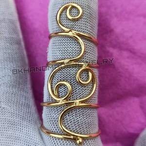 May include: Gold-toned wire ring with a swirling design. The ring is made of a single piece of wire that is twisted and shaped into a unique pattern.