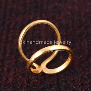 May include: Gold-toned double ring, twisted and overlapping, with a smooth, polished finish.  Bk handmade jewelry.