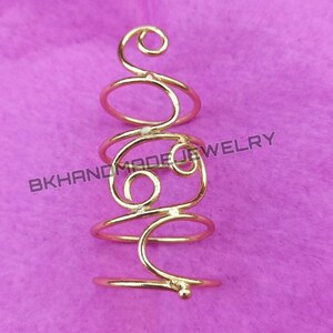May include: Gold-toned spiral ring with a delicate design. The ring is made of wire and has a small bead at the bottom.