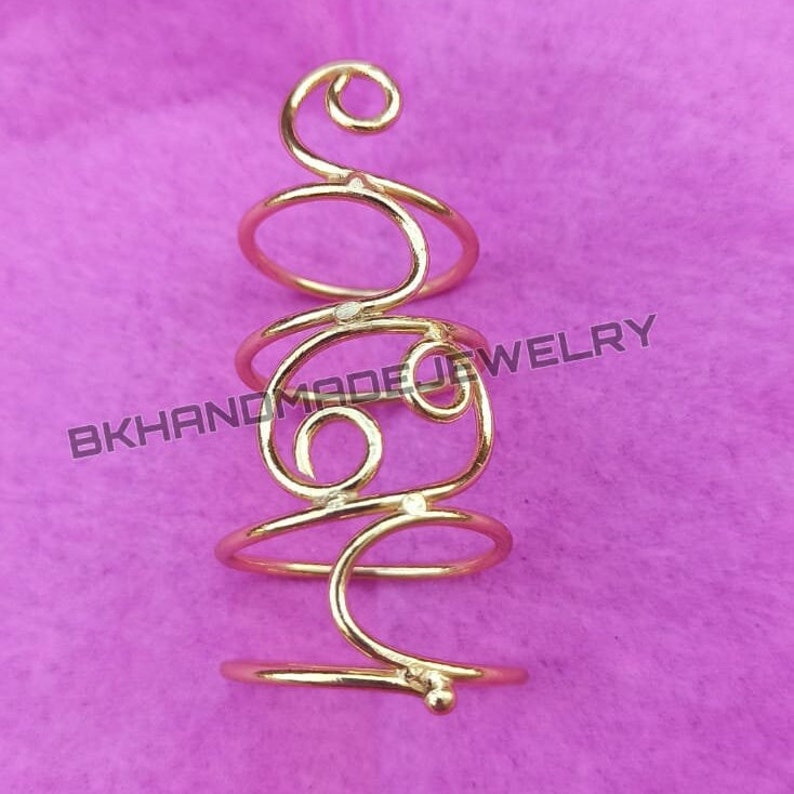 May include: Gold-toned spiral ring with a delicate design. The ring is made of wire and has a small bead at the bottom.