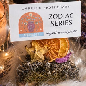 May include: A clear plastic pouch containing a simmer pot kit with dried lavender, herbs, a star fruit slice, and orange slices. The label reads Empress Apothecary Zodiac Series Aquarius magical simmer pot kit with a graphic of a vase.