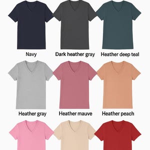 May include: Nine different colored unisex V-neck tees are displayed. Colors include navy, dark heather gray, heather deep teal, heather gray, heather mauve, heather peach, pink, sand, and red. The text "UNISEX V-NECK TEES" is at the top.