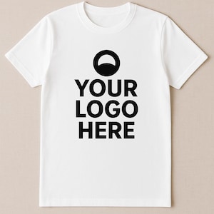 May include: White crew neck t-shirt with the text "YOUR LOGO HERE" in bold black letters. Above the text is a black semi-circle. The t-shirt is short-sleeved and made of a soft material.