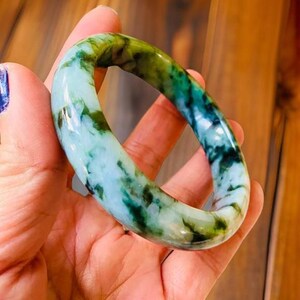 Puede incluir: Un brazalete de jade con un patr&oacute;n de m&aacute;rmol verde y blanco.
