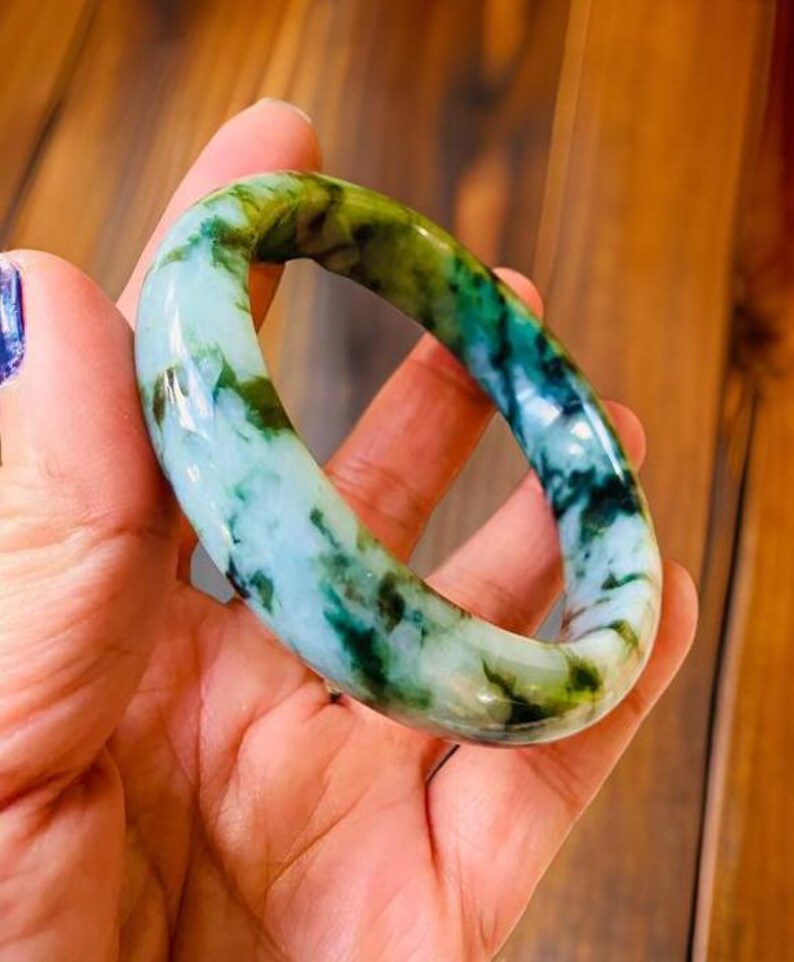 Puede incluir: Un brazalete de jade con un patr&oacute;n de m&aacute;rmol verde y blanco.