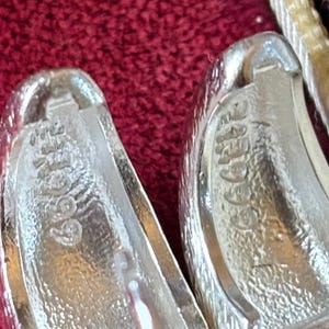 Pode incluir: Um par de brincos de argola em tom prateado com acabamento texturizado. O interior de cada brinco est&aacute; gravado com o texto 925 e 1999. Os brincos apresentam um mecanismo de fecho com pino articulado para uma fixa&ccedil;&atilde;o segura.