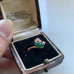 May include: A green jade ring with a rose gold setting and small diamonds. The ring is in a small, brown velvet box with the inscription "J.W. BAILEY Watchmaker & Jeweller 32 COVENTRY RD. BIRMINGHAM."