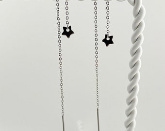 May include: A pair of silver chain earrings with star-shaped charms hanging from the ends.