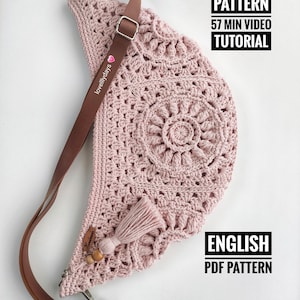 Può includere: Una borsa rosa all'uncinetto con una tracolla in pelle marrone e un fiocco. La borsa ha un motivo circolare e il testo "PATTERN 57 MIN VIDEO TUTORIAL" e "ENGLISH PDF PATTERN" è visibile.