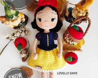 May include: Crocheted Snow White doll with a red bow, yellow skirt, blue top, and red shoes. The doll is surrounded by red apples and a gnome figurine.