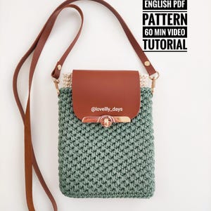 May include: A sage green crochet crossbody bag with a brown leather flap and strap. The bag has a gold-coloured clasp and a cream interior. The image includes text that reads "ENGLISH PDF PATTERN 60 MIN VIDEO TUTORIAL".