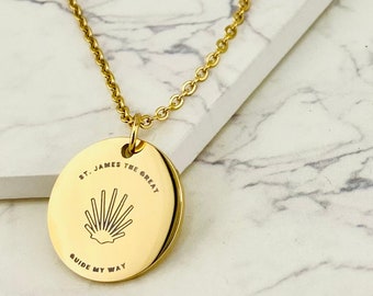 May include: Gold necklace with a round pendant featuring the text "St. James the Great" and "Guide My Way" with a scallop shell design in the center.
