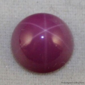 Może przedstawiać: Różowy rubin gwiaździsty z sześcioramienną gwiazdą w środku.