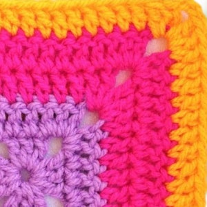 May include: A close-up of a crocheted square with a purple, pink, and orange color gradient. The square is made with a single crochet stitch and has a textured, bumpy surface.