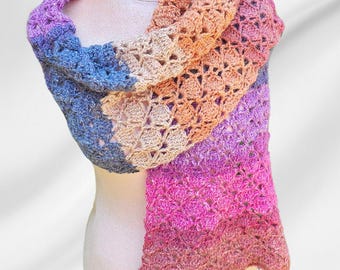 May include: A crocheted scarf with a gradient of colors, starting with purple and transitioning to pink, orange, and beige. The scarf is made with a delicate open stitch pattern.