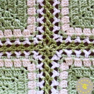 May include: Close-up of a crocheted square with a green, white, and cream color pattern. The square is made with a granny stitch and has a textured look.