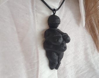 Puede incluir: Un collar negro con un colgante impreso en 3D que representa una figura femenina. El colgante es una representación estilizada del cuerpo de una mujer.